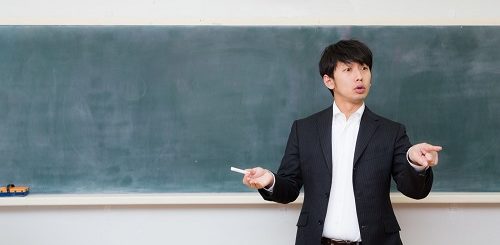 黒板の前に立って話をする教師