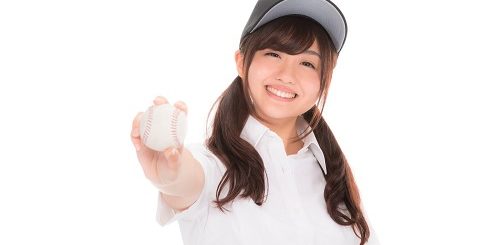 野球ボールを右手に持って前方に突き出す笑顔の女の子