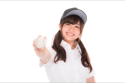 野球ボールを右手に持って前方に突き出す笑顔の女の子