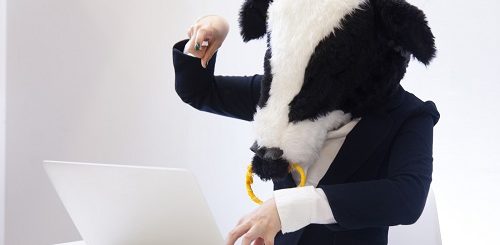 ノートパソコンを扱う牛の格好をした人